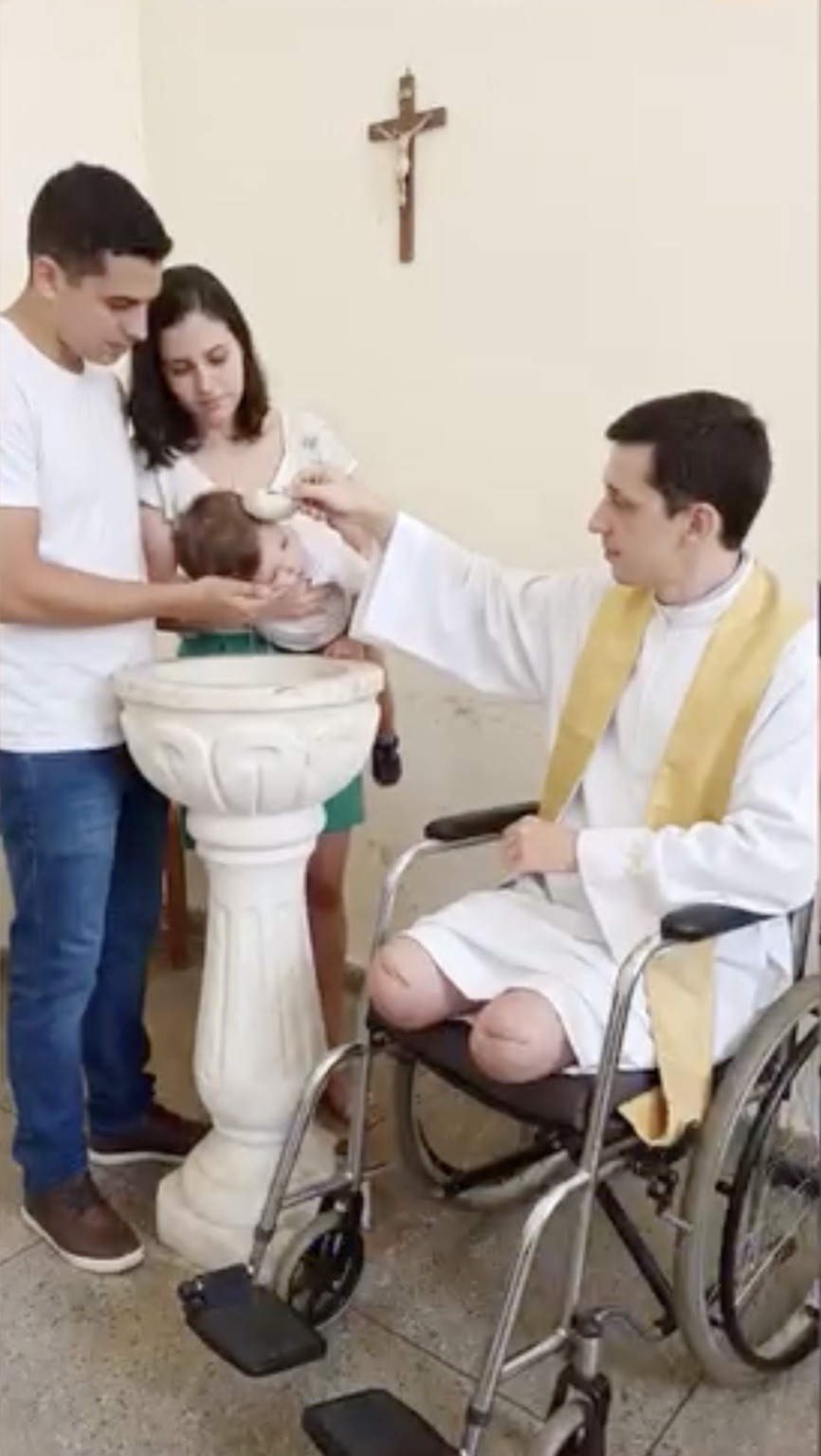Father Miguel performing a baptism while seated in his wheelchair